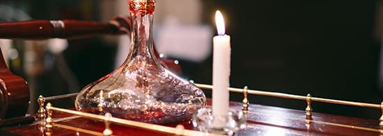 Dekanter mit Rotwein und Kerze auf Tisch