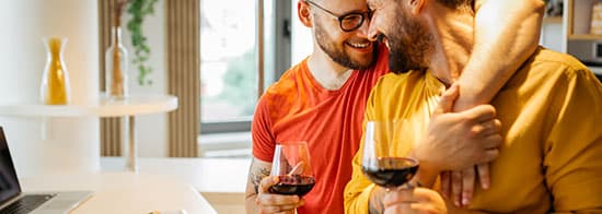 Zwei Männer umarmen sich und trinken Rotwein