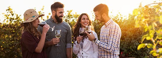 Menschen vor Weinberg mit Weingläsern in der Hand