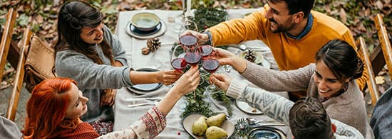 Menschen lachen und stoßen mit Rotwein an