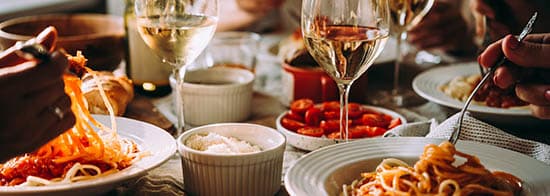 Weißweingläser auf Tisch mit Pasta