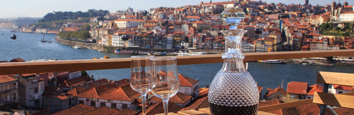 Karaffe und Rotweingläser auf Tisch vor Hafenkulisse