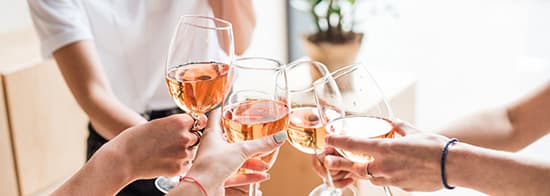 Menschen stoßen mit Roséwein an