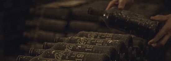 Eingestaubte Portweinflaschen in dunklem Keller