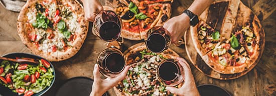 Gedeckter Tisch mit Pizza und Rotwein