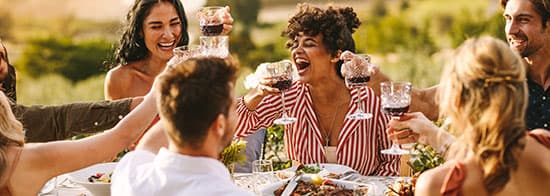 Menschen an Tisch, lachen, essen und trinken Rotwein