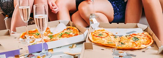 Frauen essen Pizza und trinken Sekt