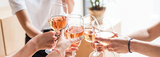 Menschen stoßen mit Roséwein an