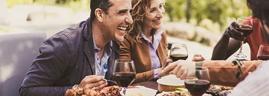 Lachende Menschen an gedeckten Tisch mit Rotweingläsern