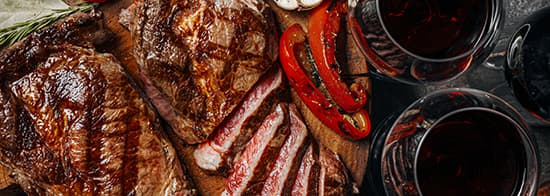 Glas Spätbegunder mit gedecktem Tisch mit Steak 