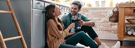 Frau und Mann sitzen auf Boden und trinken Rotwein