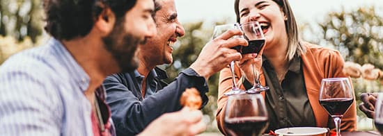 Menschen stoßen mit Wein über gedeckten Tisch an