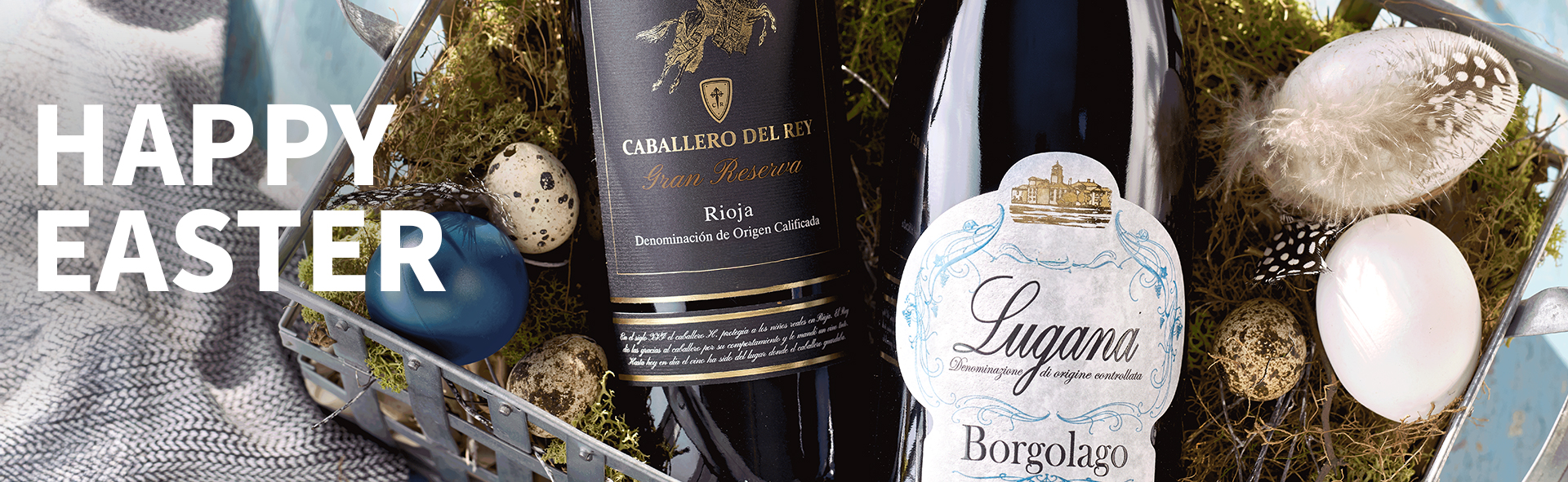Meravino Weinaktion mit dem Slogan "Happy Easter". Im Hintergrund zwei Flaschen Wein in einem Osterkörbchen.